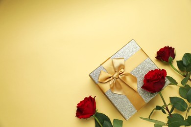 Romantic gift and roses on beige background, flat lay. Space for text