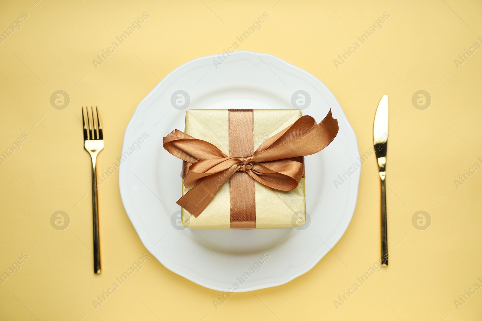 Photo of Beautiful table setting with romantic gift on beige background, flat lay