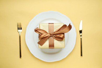 Beautiful table setting with romantic gift on beige background, flat lay