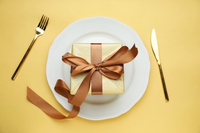 Beautiful table setting with romantic gift on beige background, flat lay