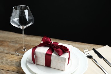 Beautiful table setting with romantic gift on wooden background