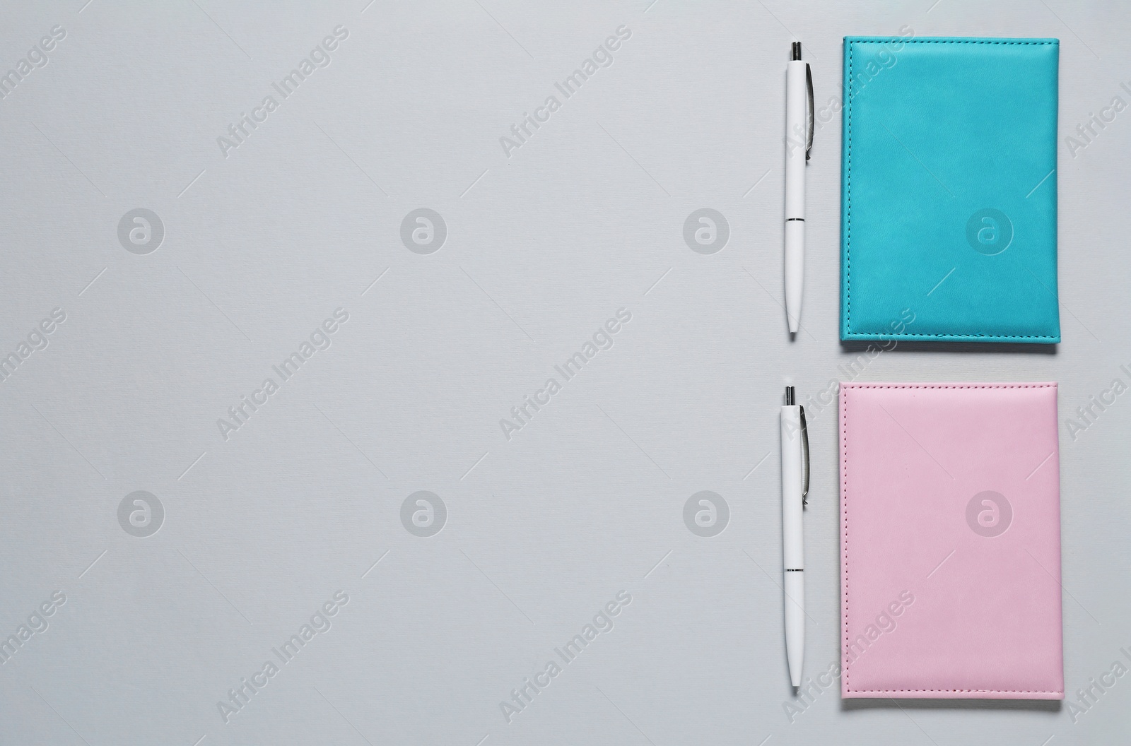 Photo of Blank covers and pens for branding on gray background, flat lay. Mockup for design