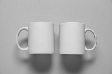 Photo of Blank cups for branding on gray background, flat lay. Mockup for design