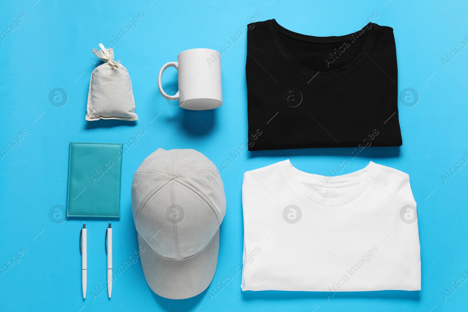 Photo of Different blank items for branding on light blue background, flat lay. Mockup for design