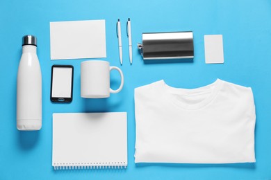 Photo of Different blank items for branding on light blue background, flat lay. Mockup for design