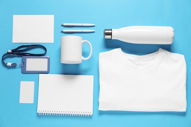 Photo of Different blank items for branding on light blue background, flat lay. Mockup for design