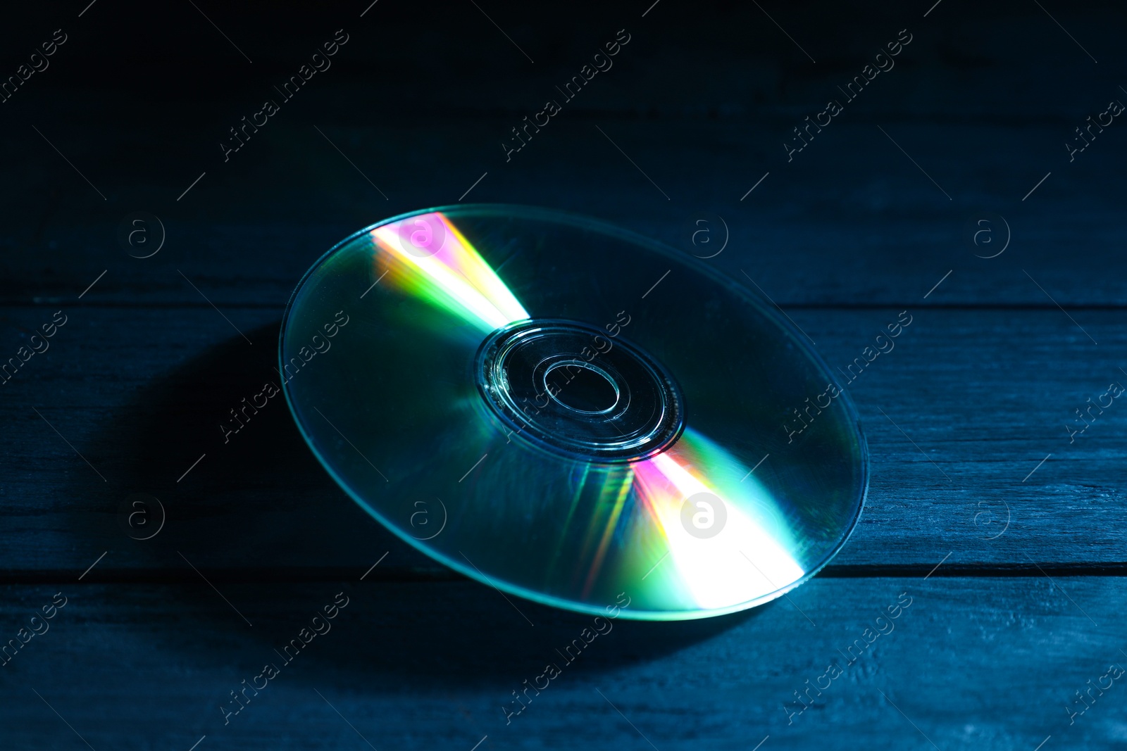 Photo of One compact disc on wooden background, closeup