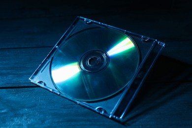 Photo of One compact disc in jewel case on wooden background, closeup