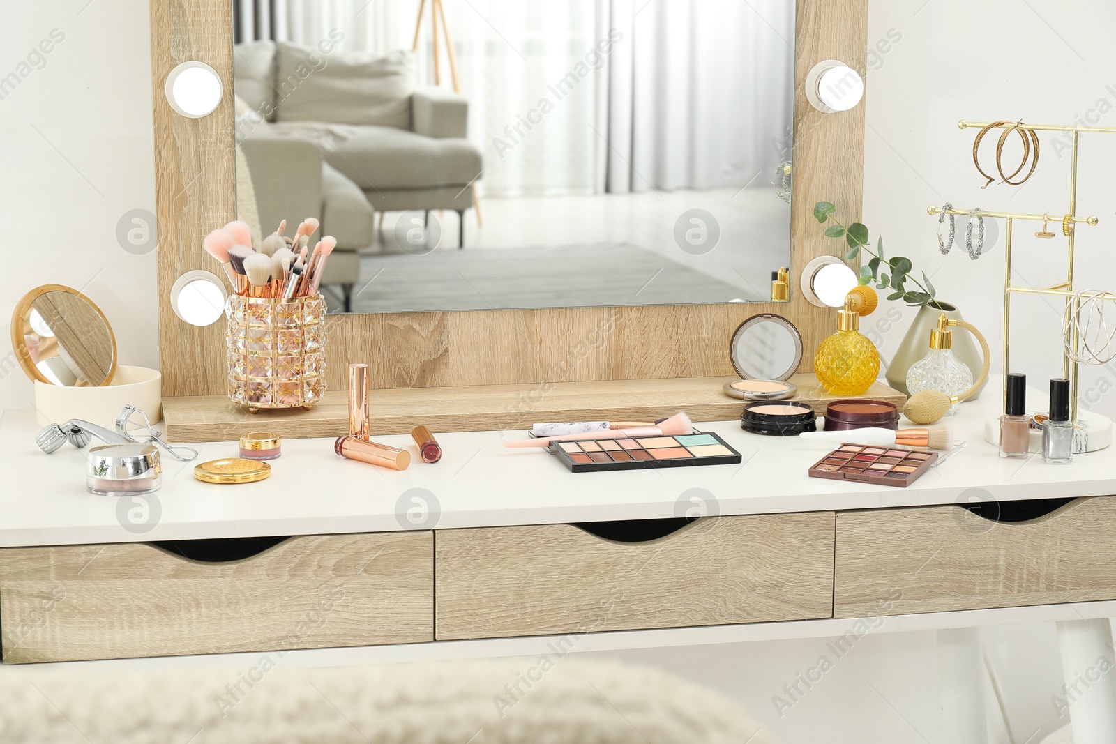 Photo of Makeup room. Dressing table with mirror, different beauty products and jewelry indoors