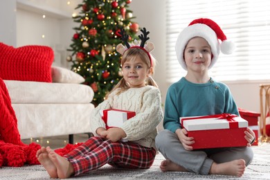 Happy children with Christmas gifts on floor at home