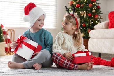 Photo of Happy children with Christmas gifts on floor at home