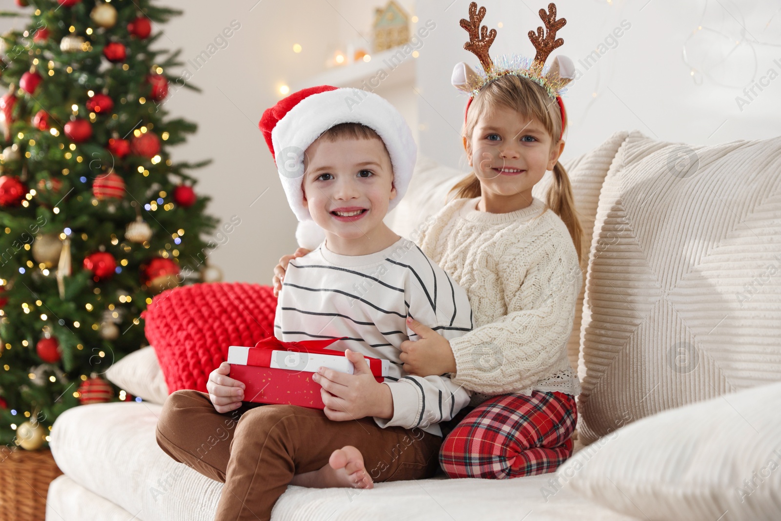 Photo of Happy children with Christmas gift on sofa at home