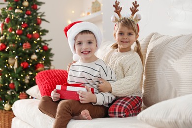 Photo of Happy children with Christmas gift on sofa at home