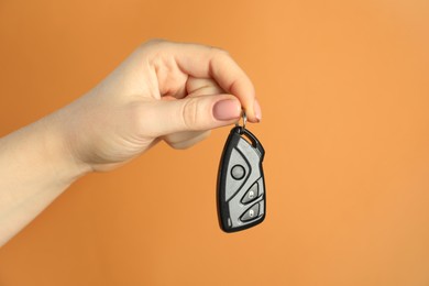 Photo of Woman with car flip key on orange background, closeup