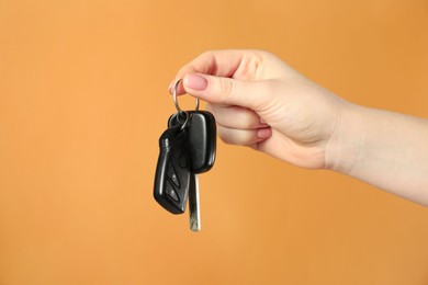 Photo of Woman with car keys on orange background, closeup