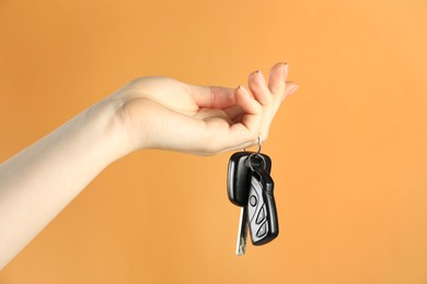 Photo of Woman with car keys on orange background, closeup