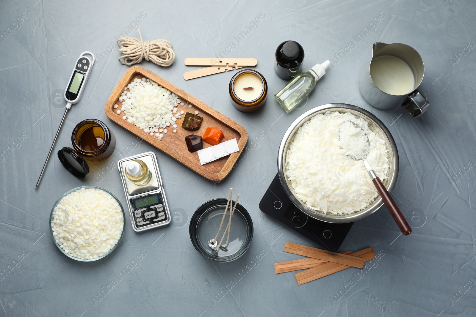 Photo of Soy wax, essential oils and different tools for making candles on gray textured table, flat lay