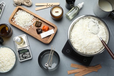 Photo of Soy wax, essential oils and different tools for making candles on gray textured table, flat lay