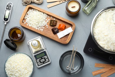 Photo of Soy wax, essential oil and different tools for making candles on gray textured table, flat lay