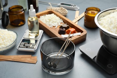 Photo of Soy wax, essential oil and different tools for making candles on gray textured table, closeup