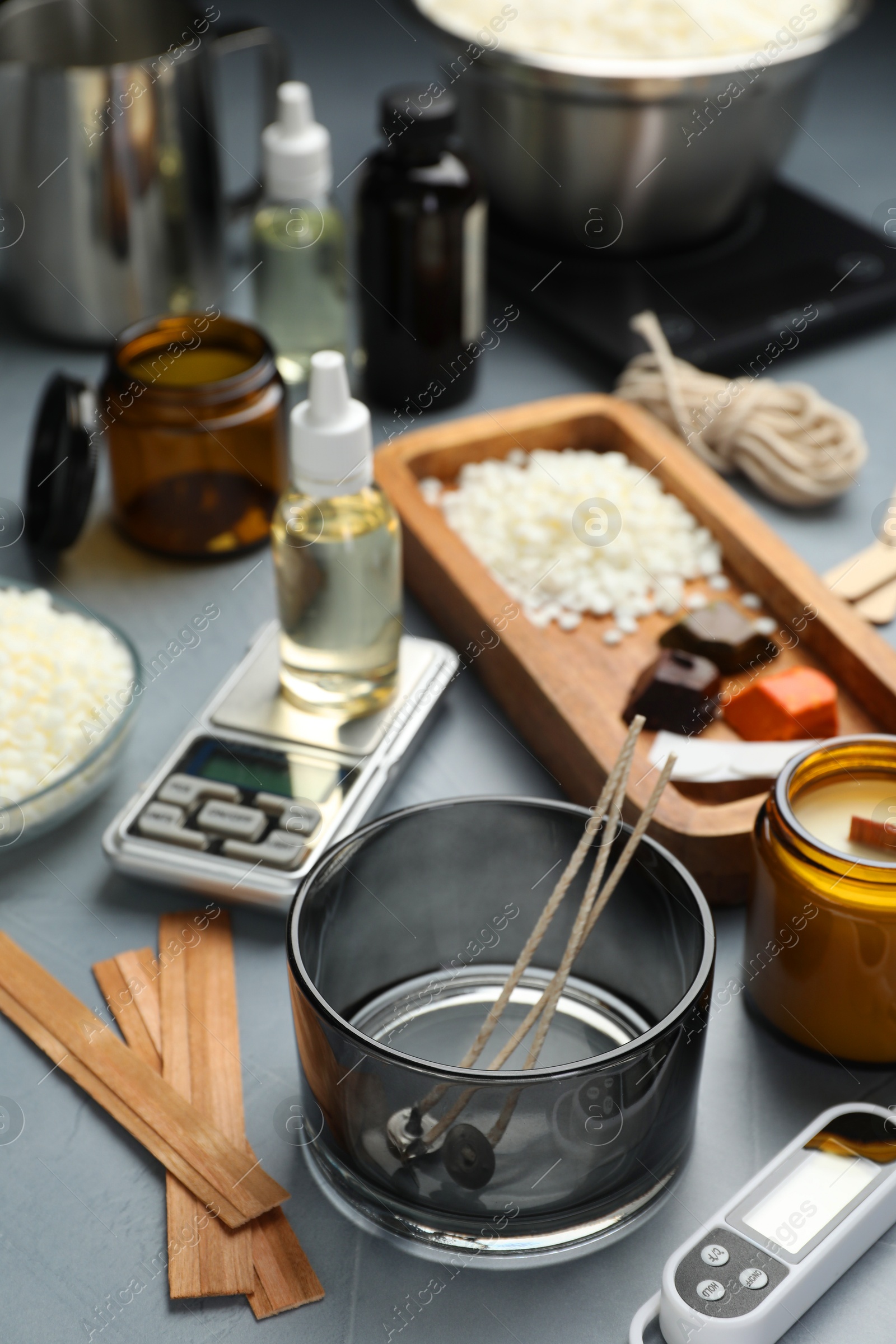 Photo of Soy wax, essential oils and different tools for making candles on gray table, selective focus