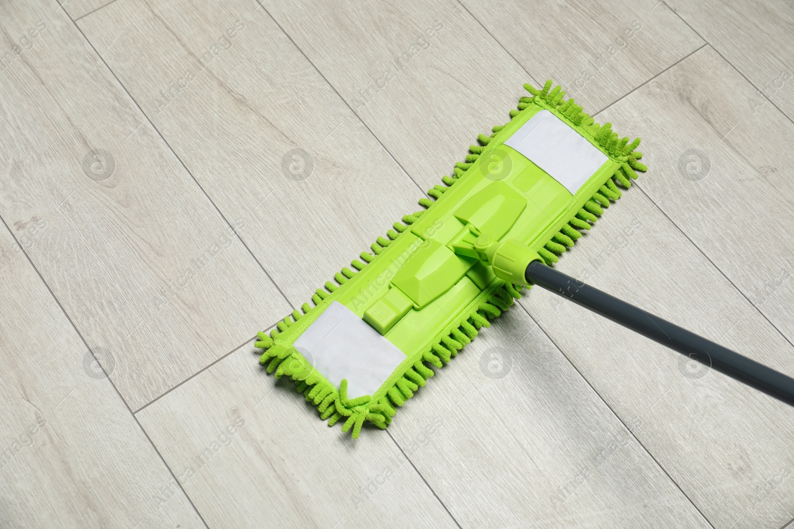 Photo of Microfiber mop on wooden floor, space for text