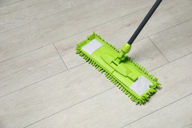 Photo of Microfiber mop on wooden floor, space for text