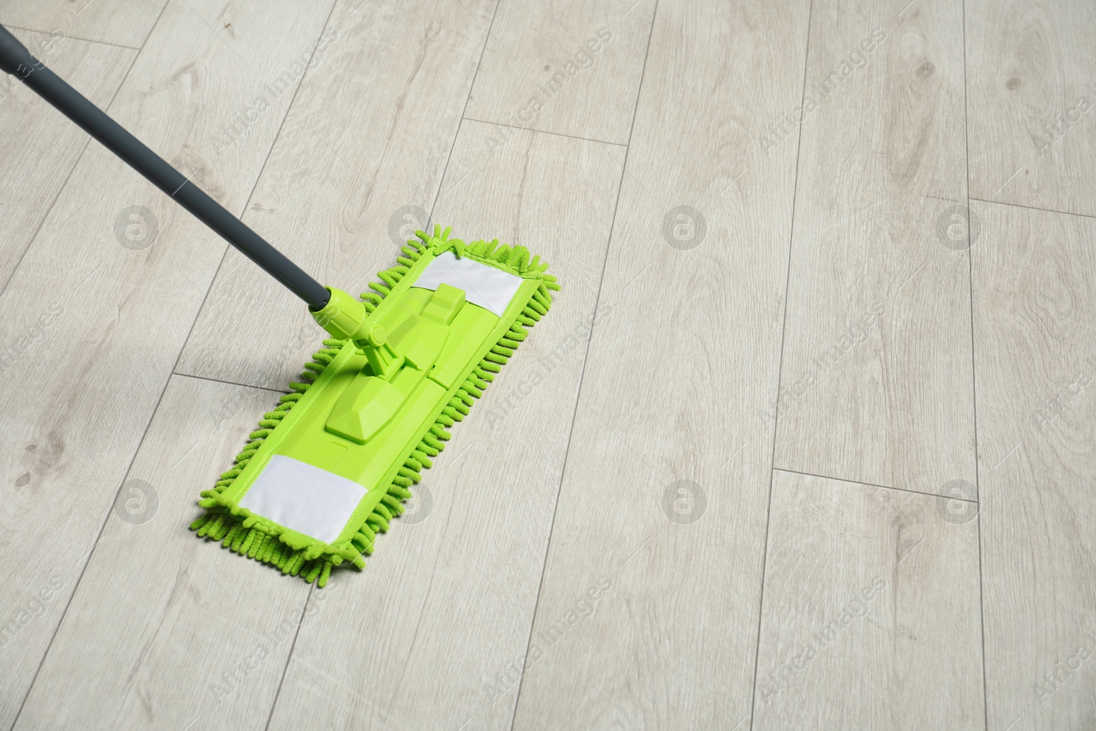 Photo of Microfiber mop on wooden floor, space for text