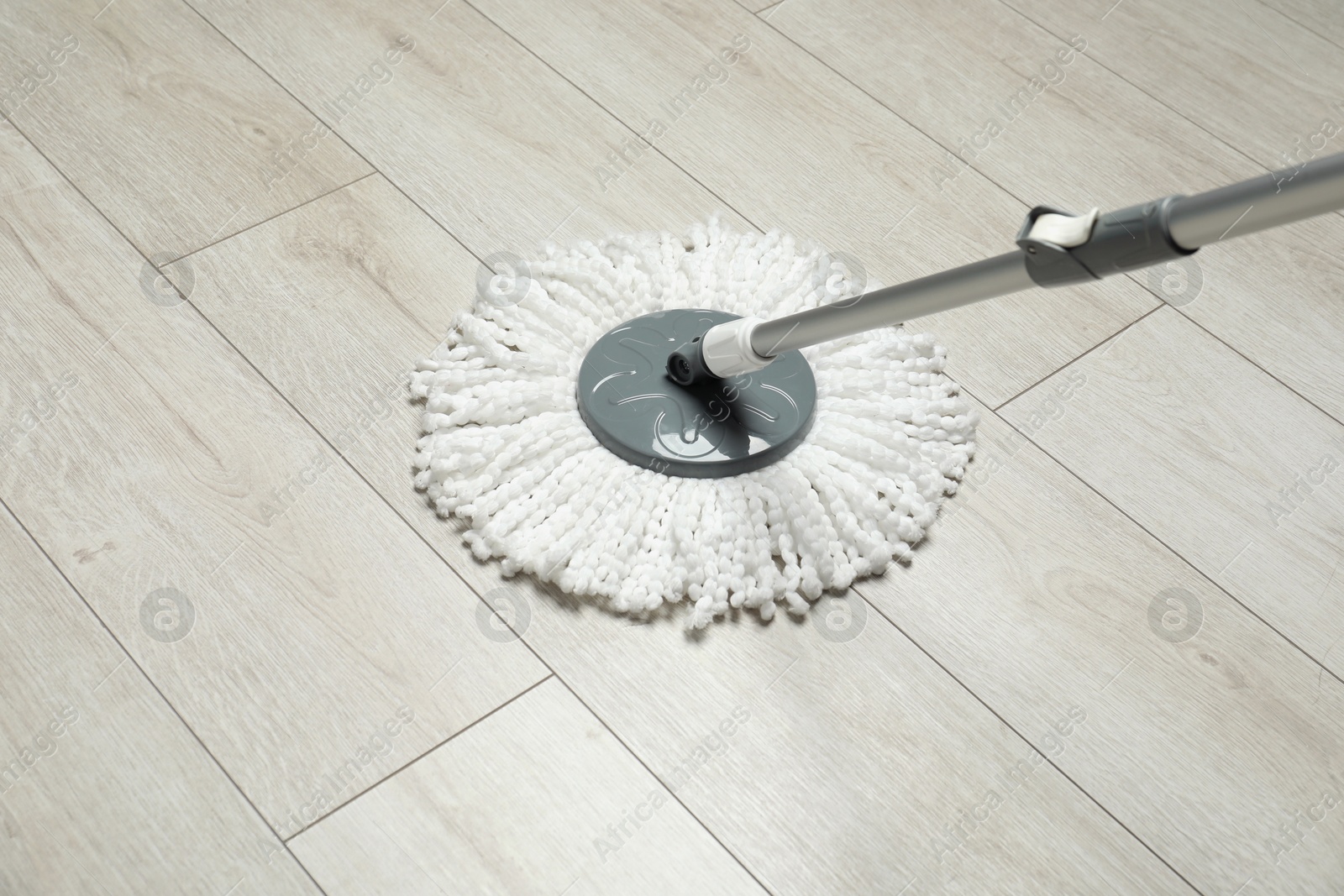 Photo of String mop on wooden floor. Cleaning equipment