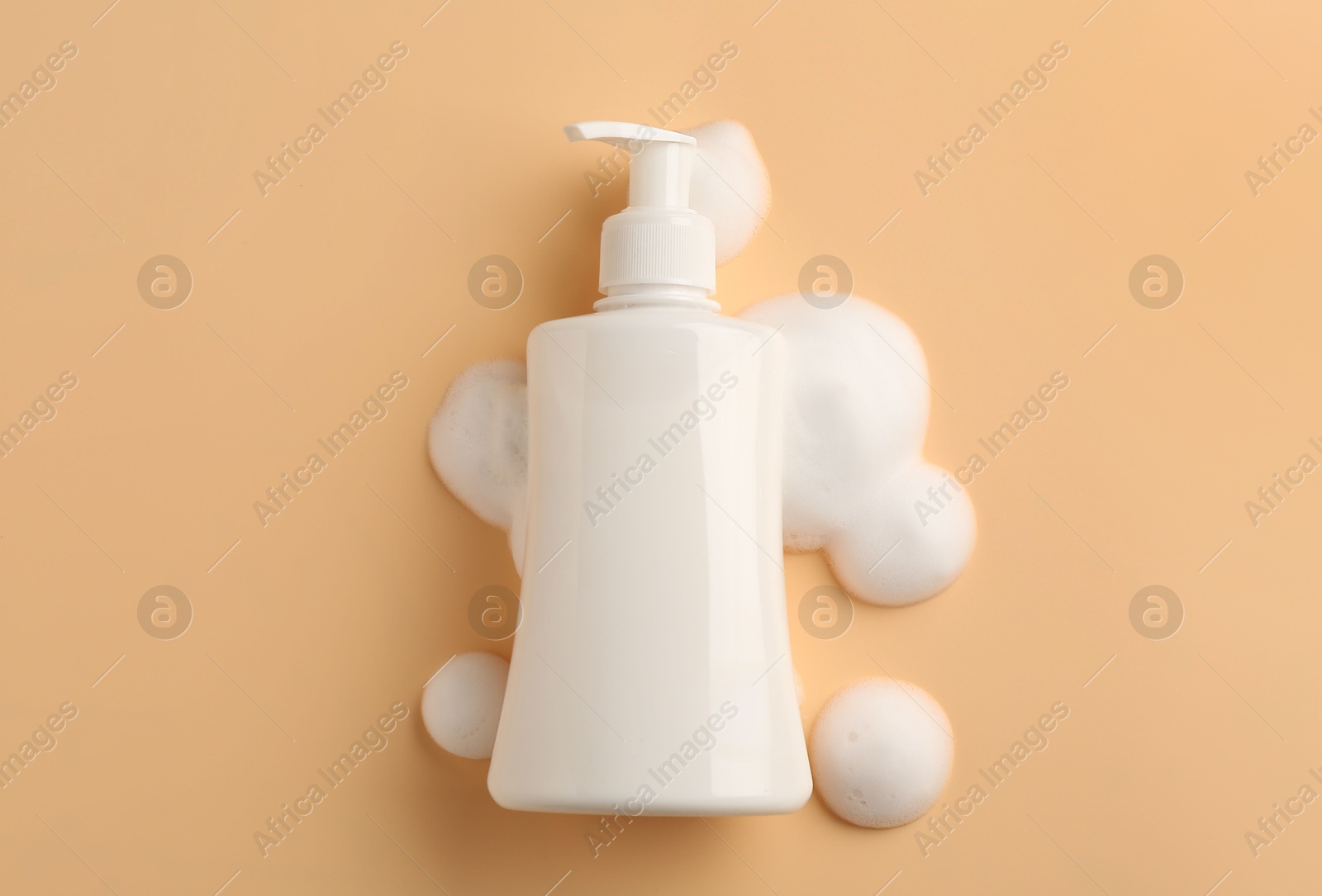 Photo of Bottle of cosmetic product with foam on beige background, top view