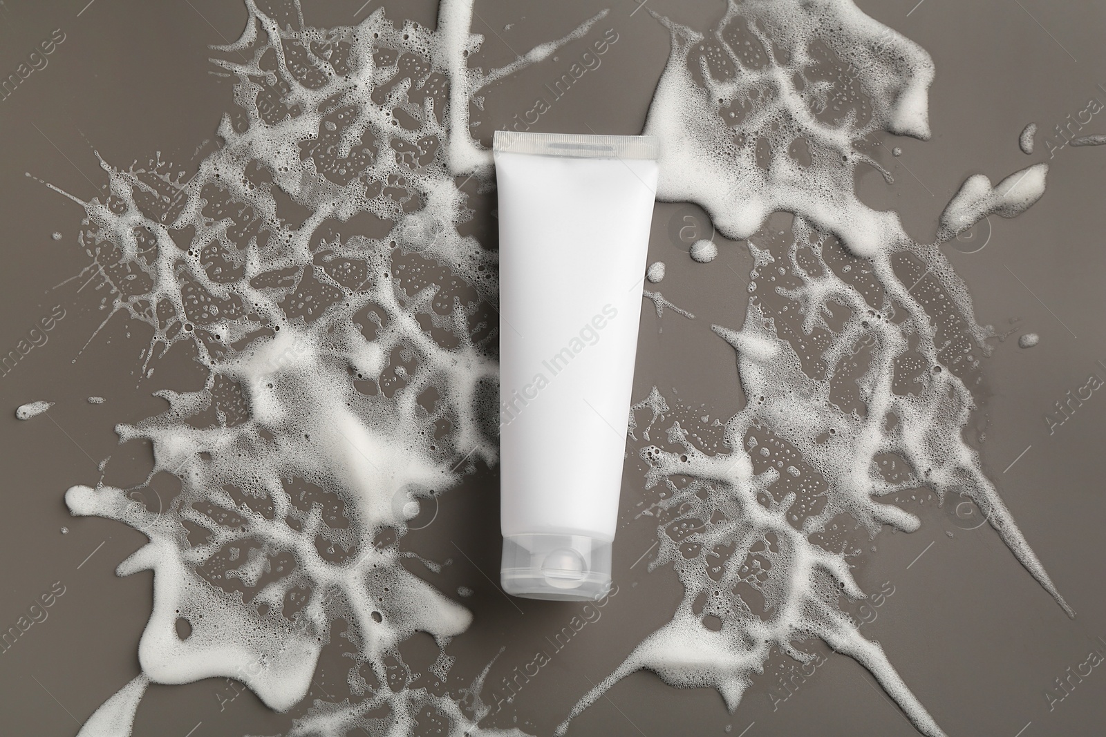 Photo of Tube of cosmetic product with foam on grey background, top view