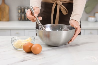 Photo of Woman making dough at white marble table indoors, closeup