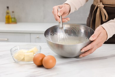 Photo of Woman making dough at white marble table indoors, closeup. Space for text