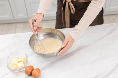 Photo of Woman making dough at white marble table indoors, closeup