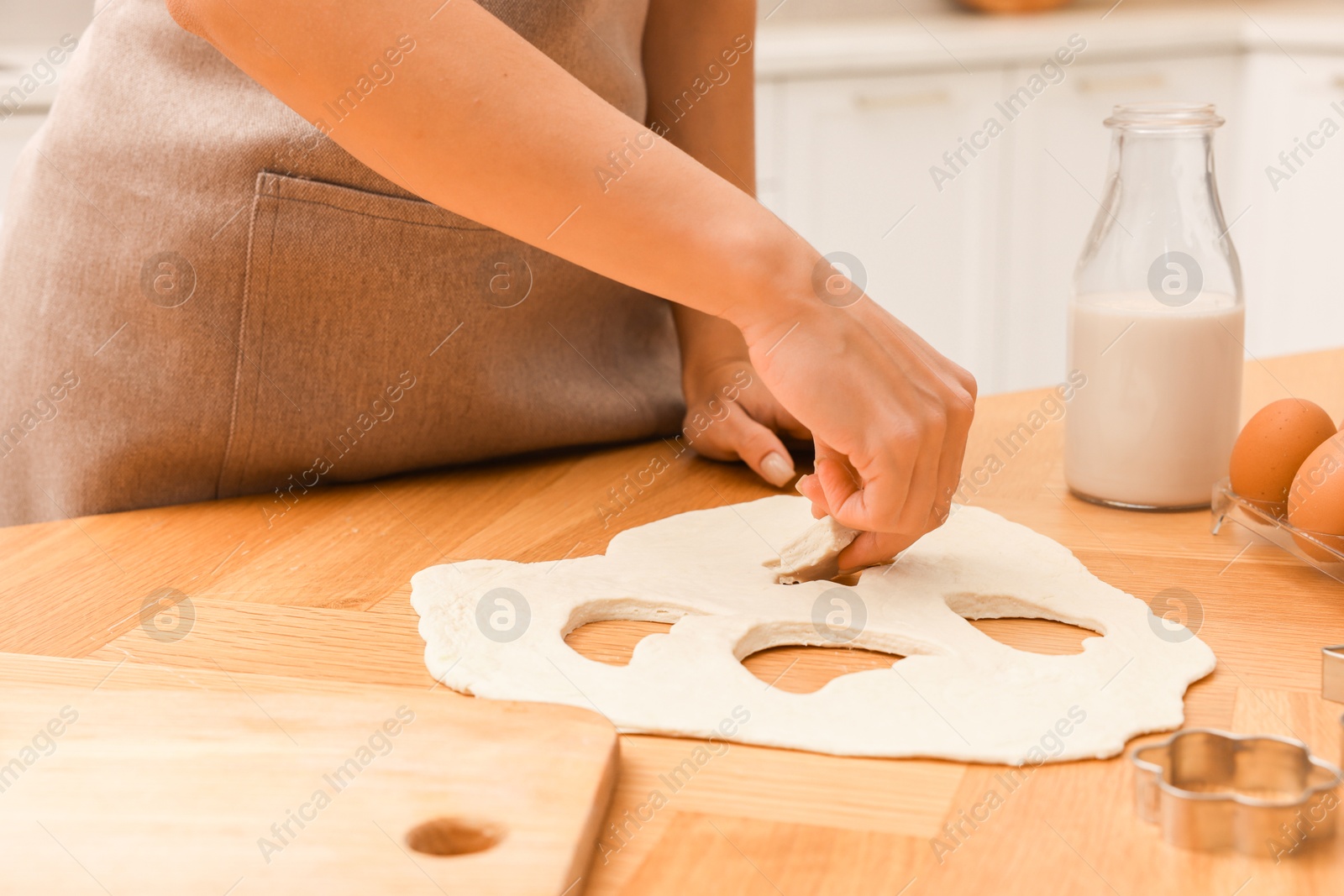 Photo of Woman with raw cookies at wooden table, closeup