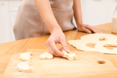 Photo of Woman with raw cookies at wooden table, closeup