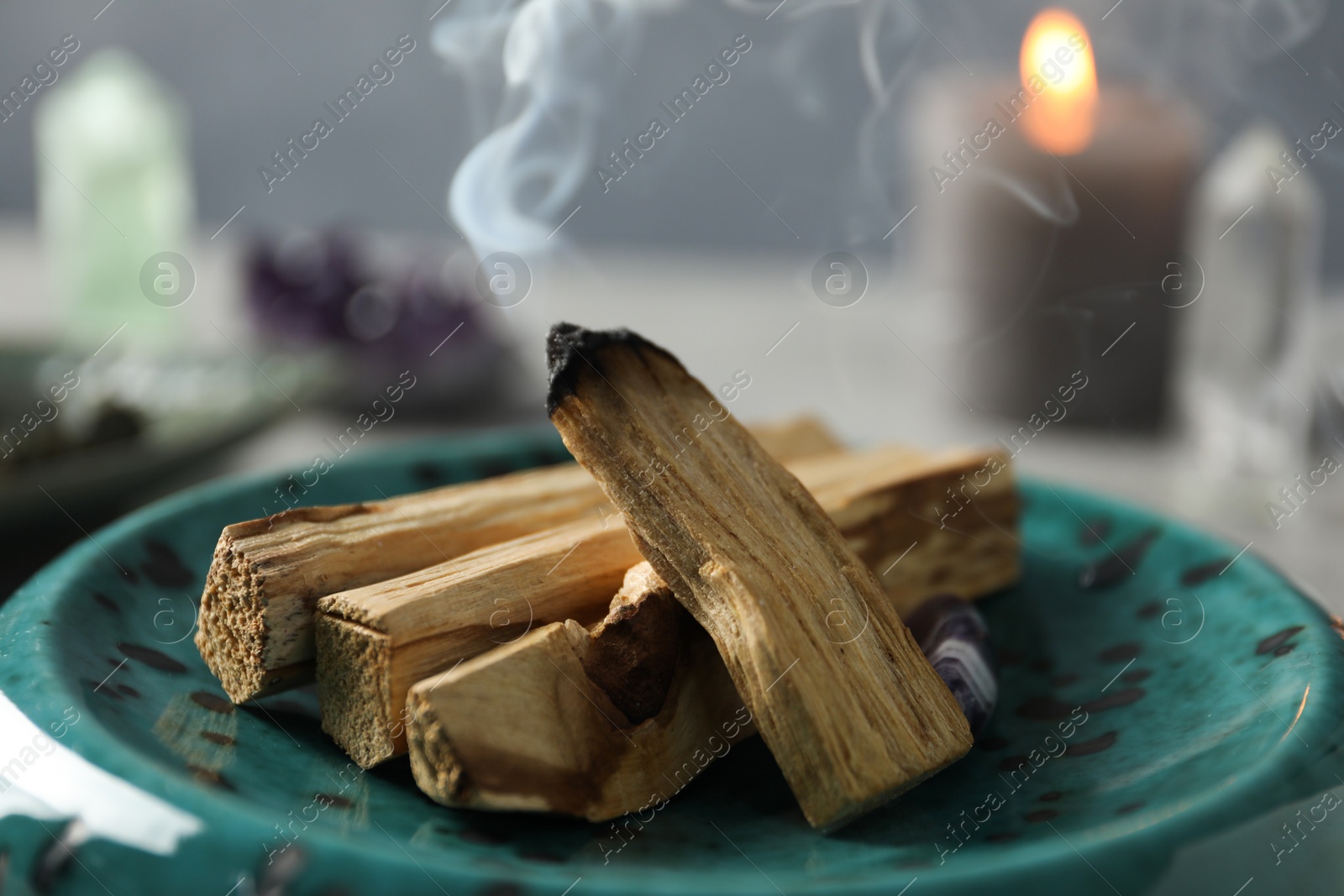 Photo of Smoldering palo santo stick on table, closeup