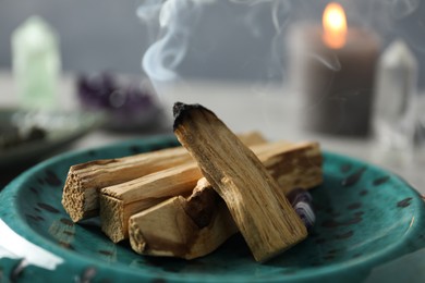 Photo of Smoldering palo santo stick on table, closeup