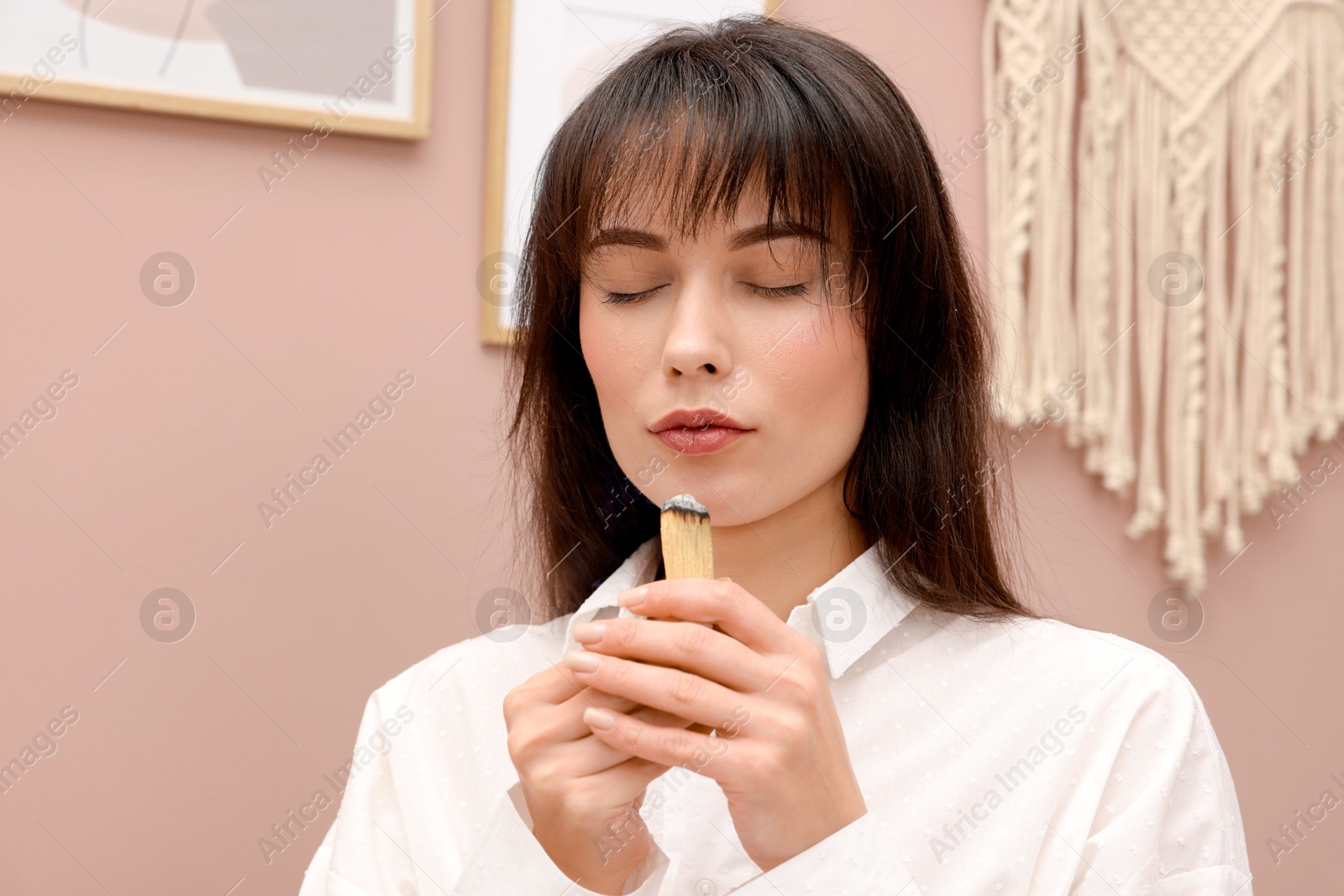 Photo of Woman with smoldering palo santo stick at home