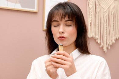 Woman with smoldering palo santo stick at home