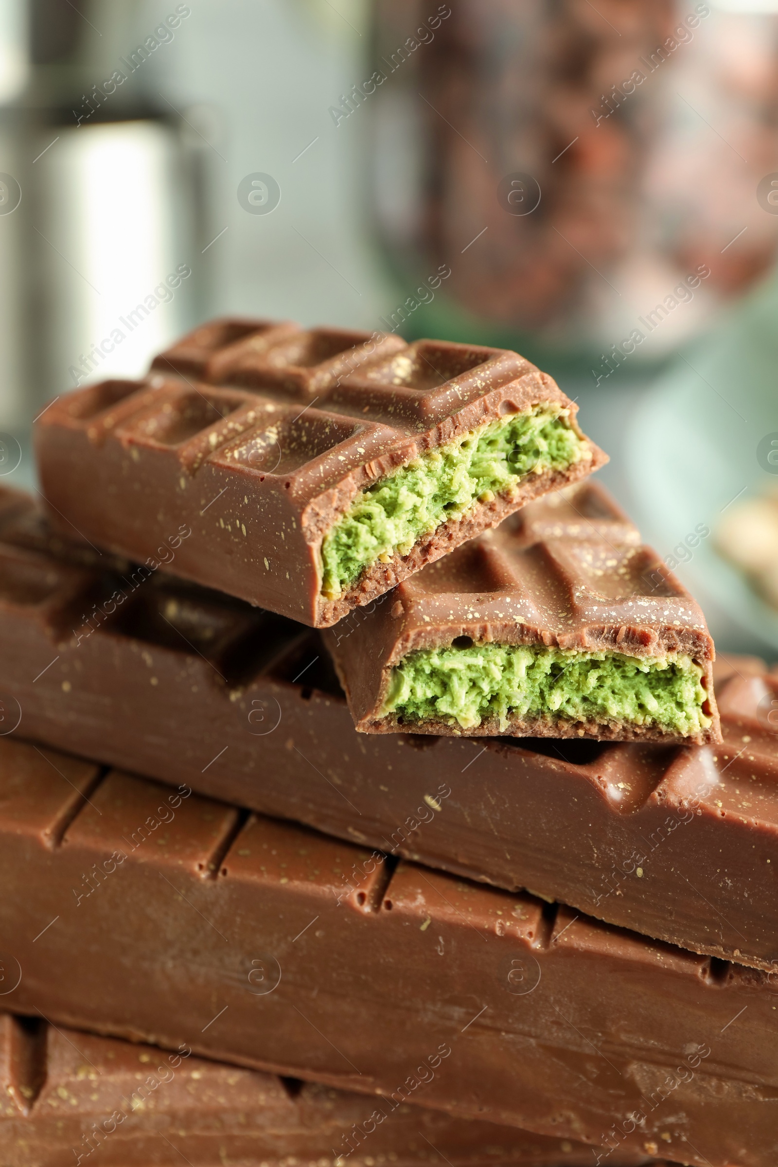 Photo of Stack of tasty Dubai chocolate bars with pistachios and knafeh on blurred background, closeup