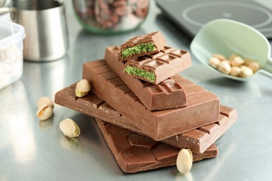 Photo of Stack of tasty Dubai chocolate bars with pistachios and knafeh on grey table, closeup