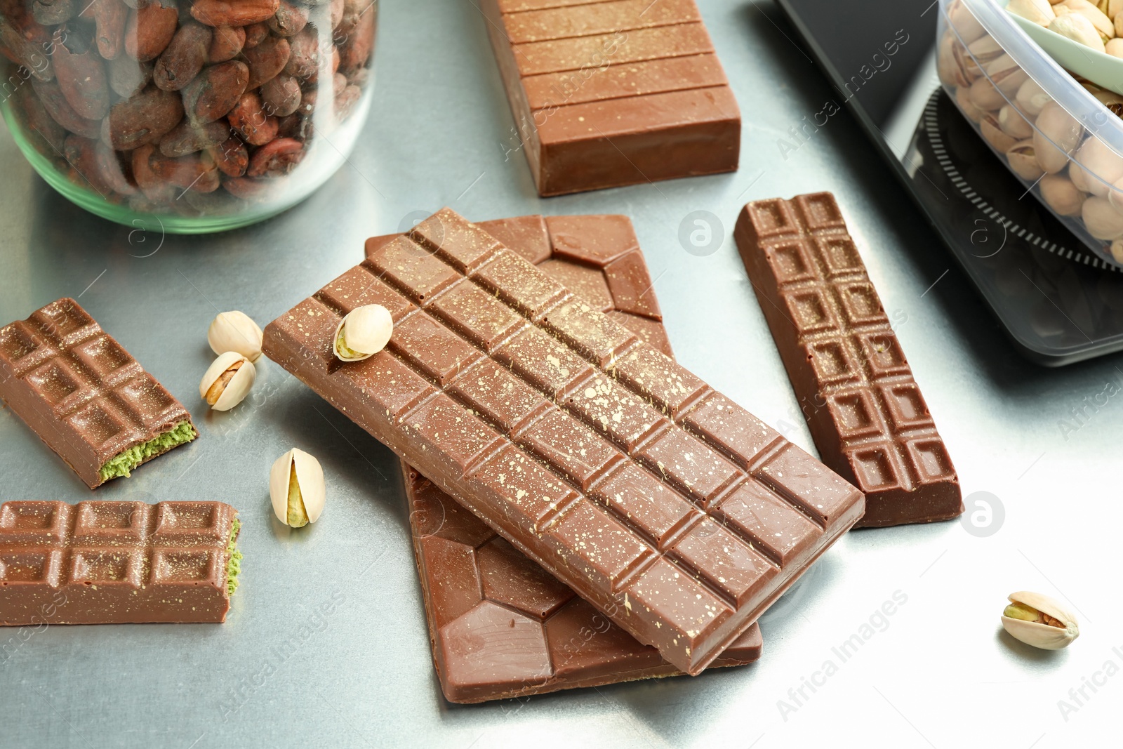 Photo of Different tasty Dubai chocolate bars with pistachios and knafeh on grey table