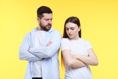 Photo of Resentful couple with crossed arms on yellow background