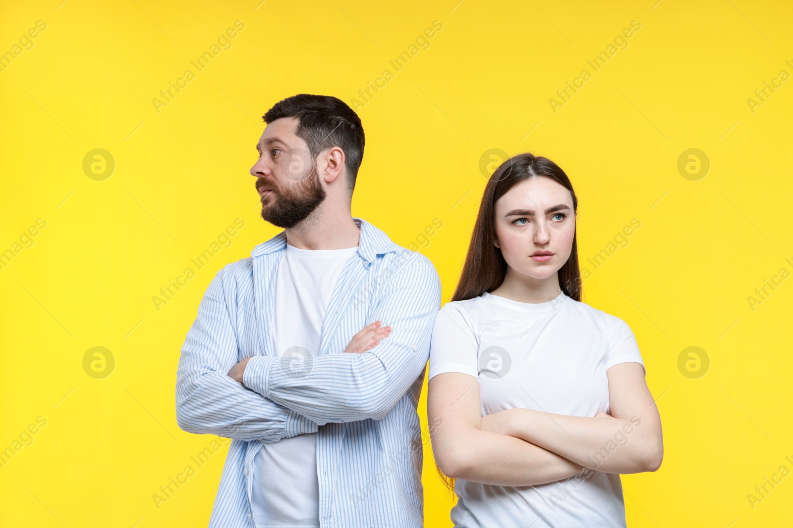 Photo of Resentful couple with crossed arms on yellow background