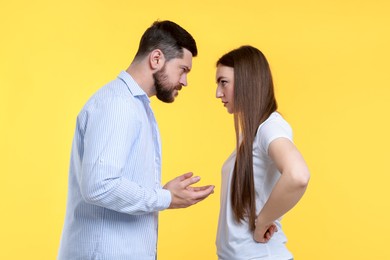 Angry couple arguing on yellow background. Relationship problem