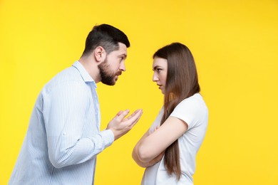 Photo of Angry couple arguing on yellow background. Relationship problem