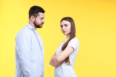 Resentful couple on yellow background. Relationship problem