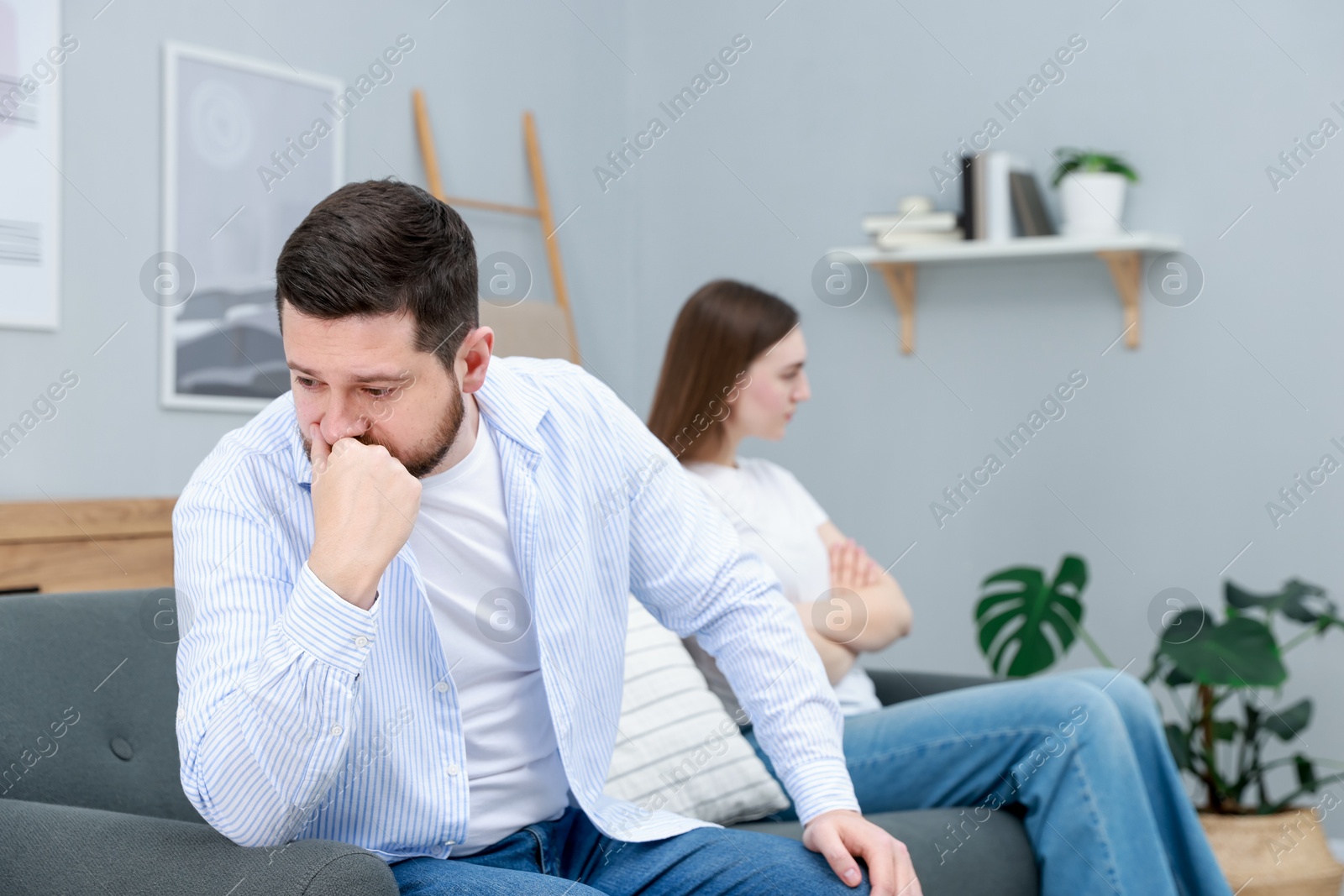 Photo of Resentful couple sitting on couch at home, selective focus