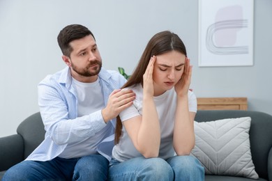 Photo of Man comforting his resentful girlfriend on couch at home